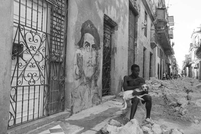 Mural del Ché en una de las calles en obras de La Habana Vieja. Un trabajador cuidando a su perro